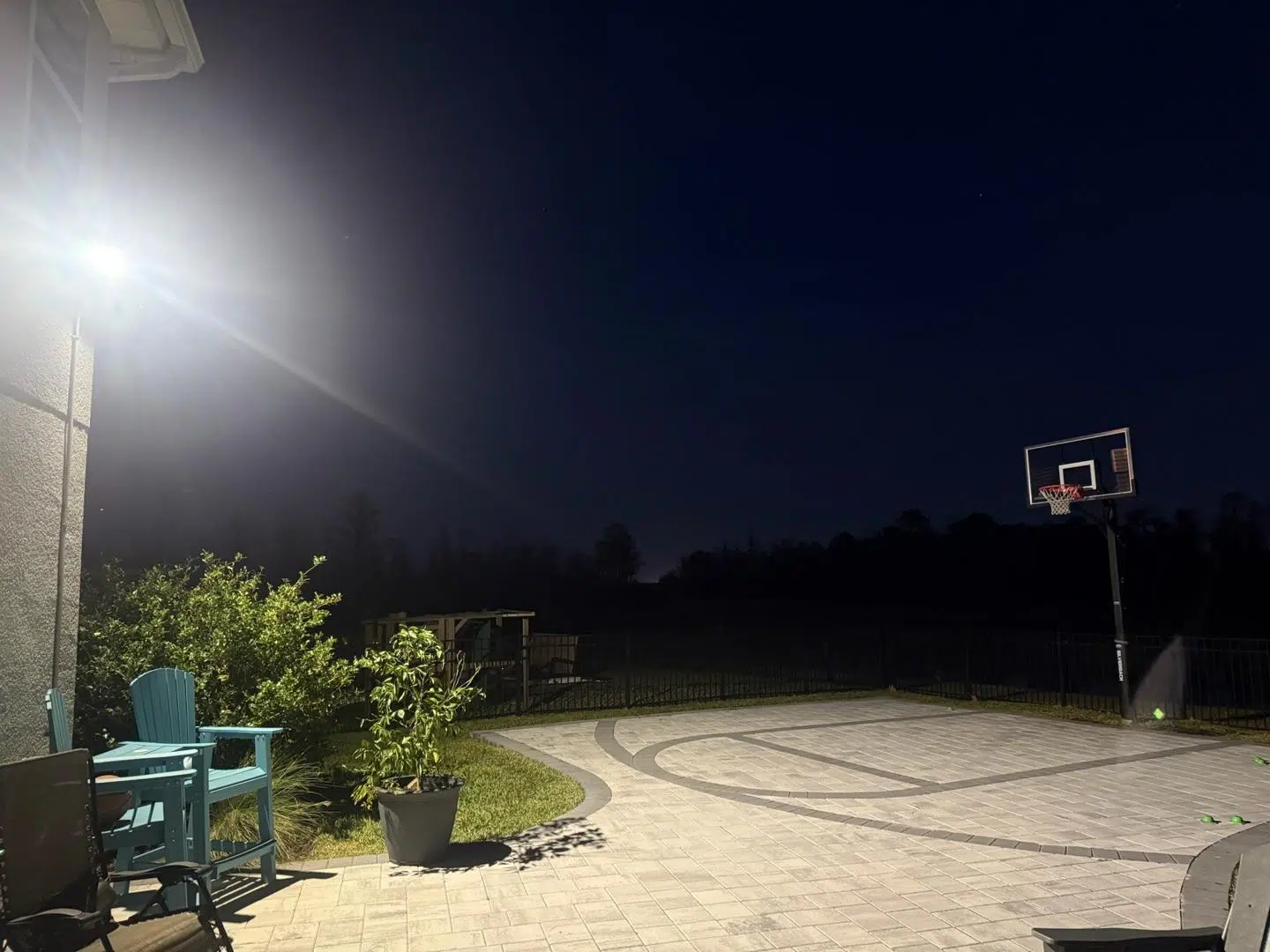 Bright floodlight illuminating a backyard basketball court at night in Spring Hill.