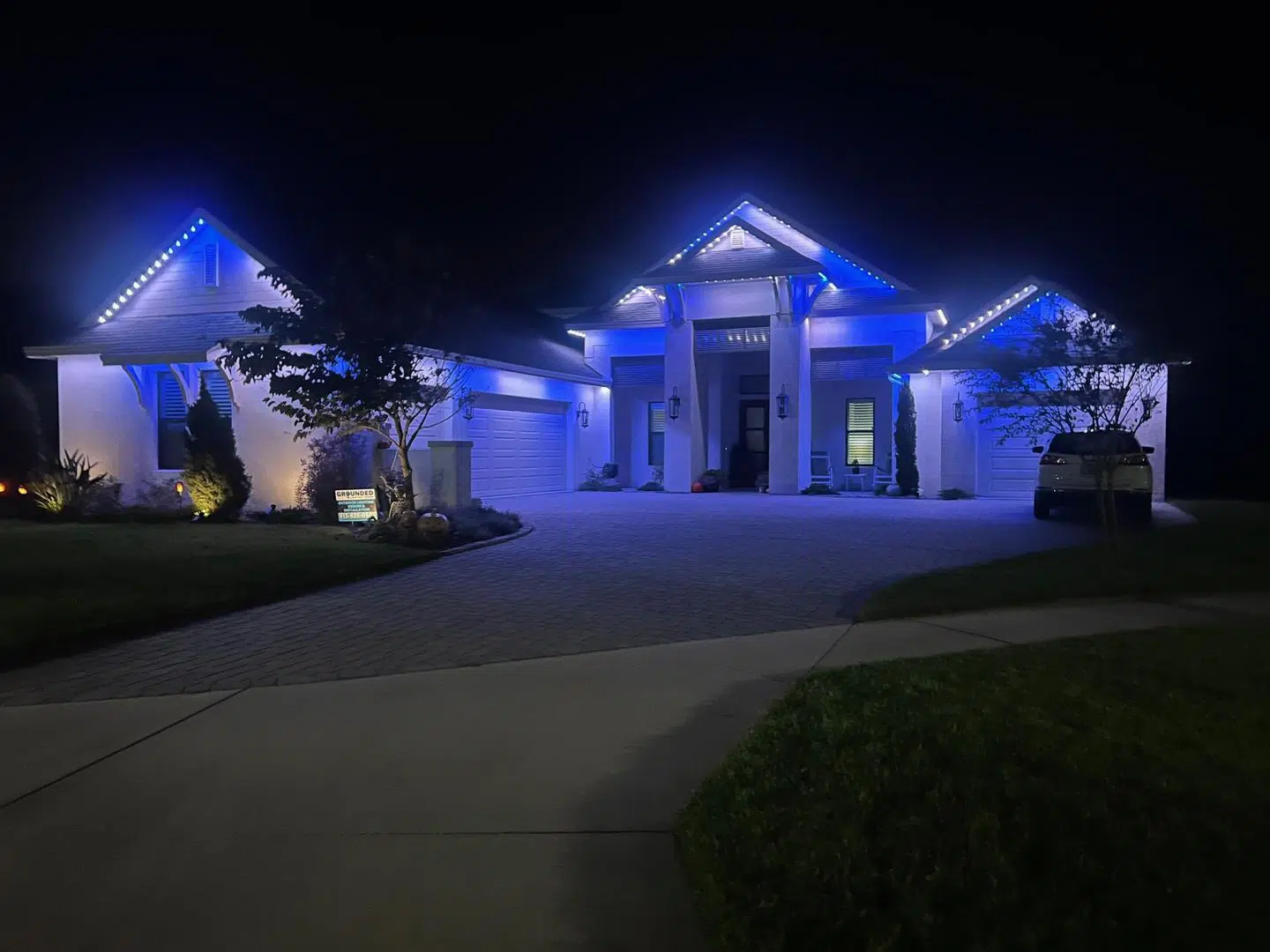 Blue LED lighting installed along the roofline and entry of a modern Odessa home.