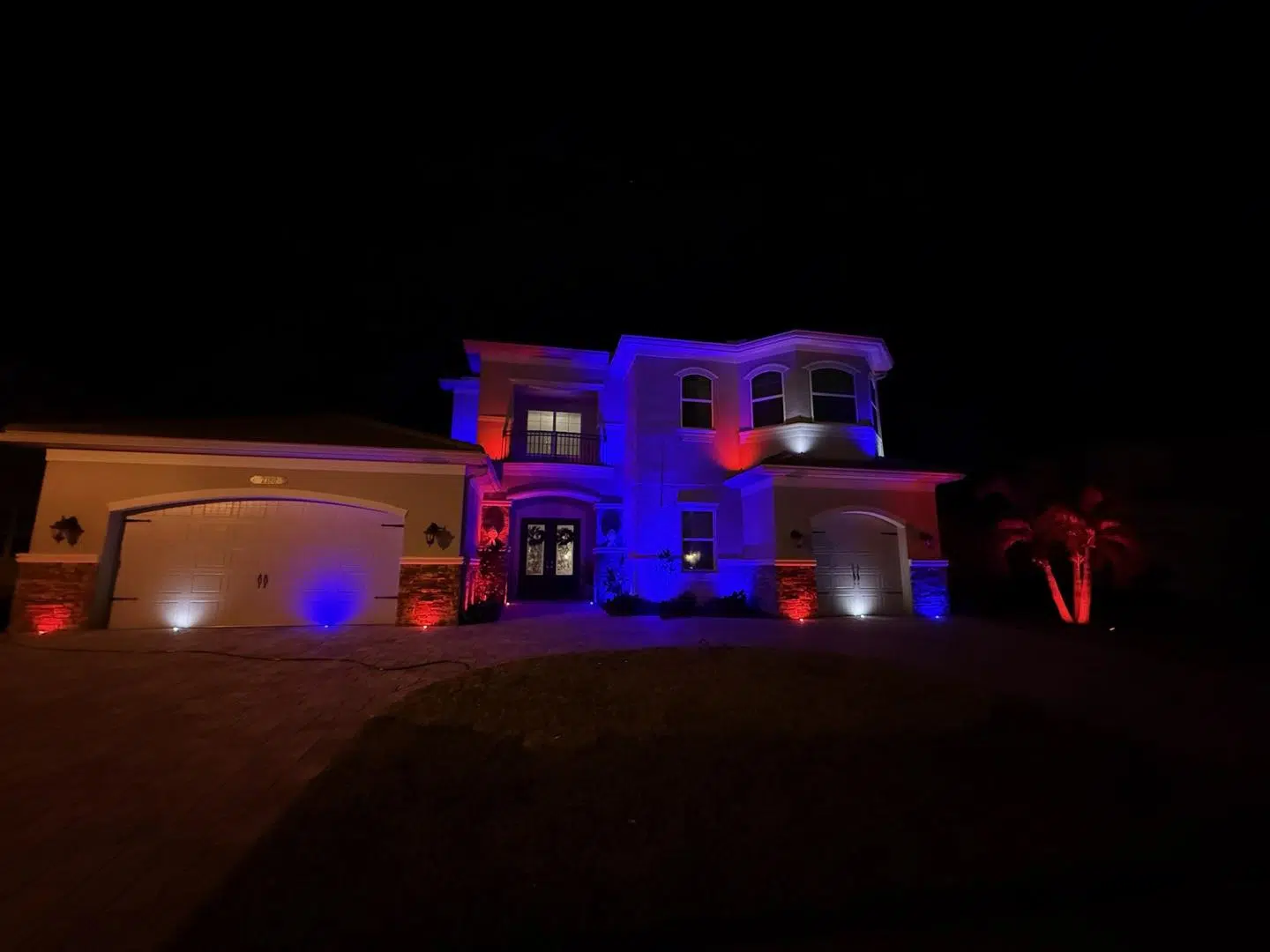 Odessa home lit with red and blue accent lighting for a striking nighttime look.