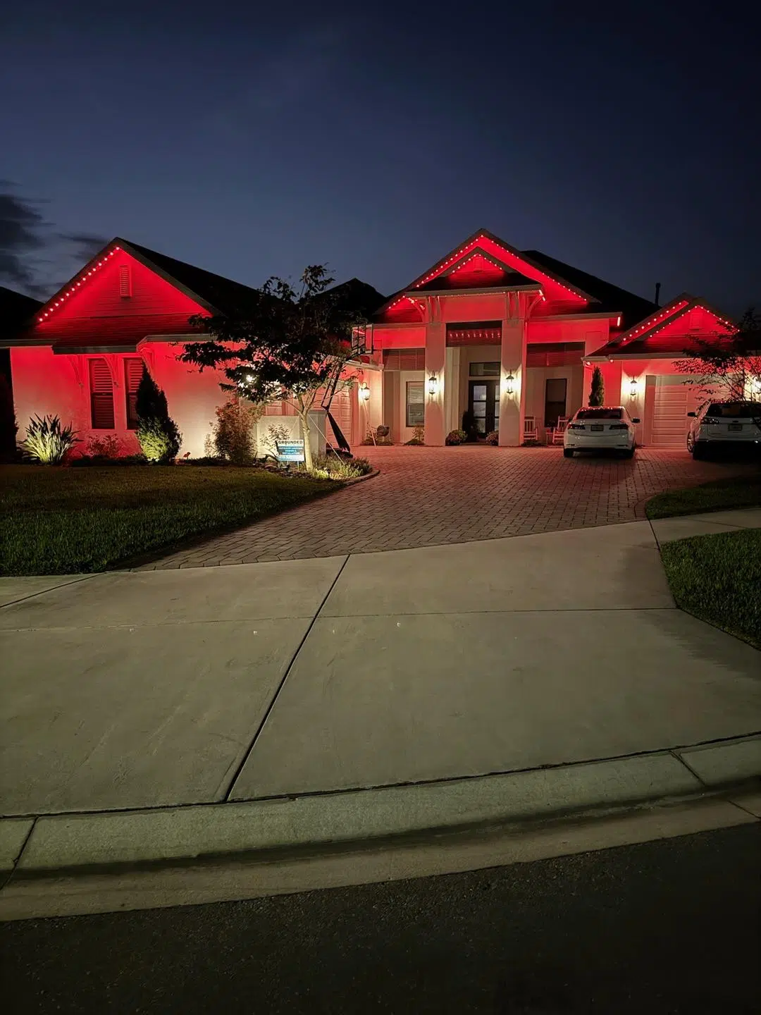 Red exterior lighting on the front of a large Wesley Chapel home at night.