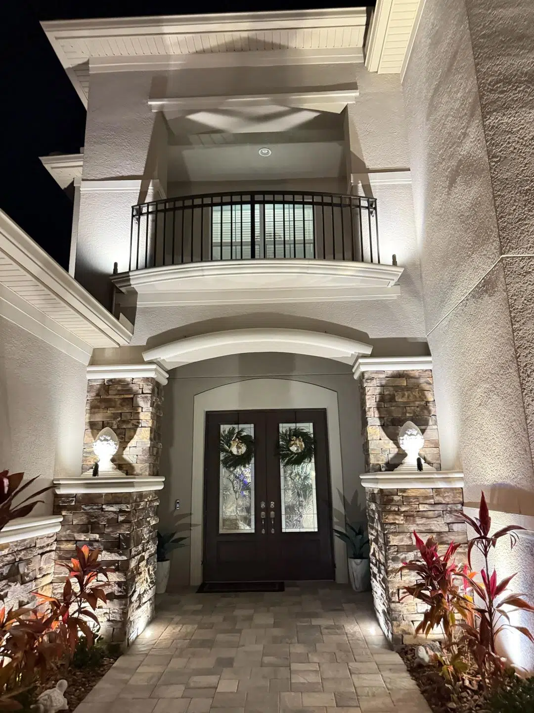 White LED lighting framing the front entrance of a luxury Trinity home with stone accents.