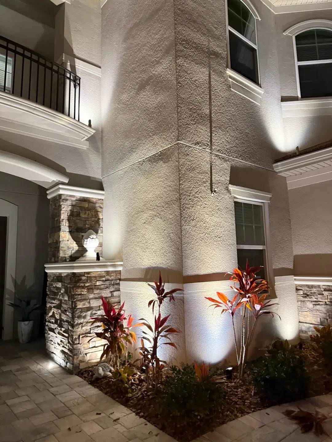 Focused uplighting on textured stone and landscaping at the front of an Odessa residence.