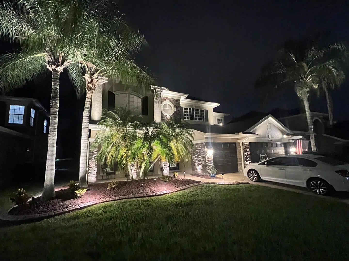 Soft white lighting on palm trees and architecture at a two-story home in Land O' Lakes.