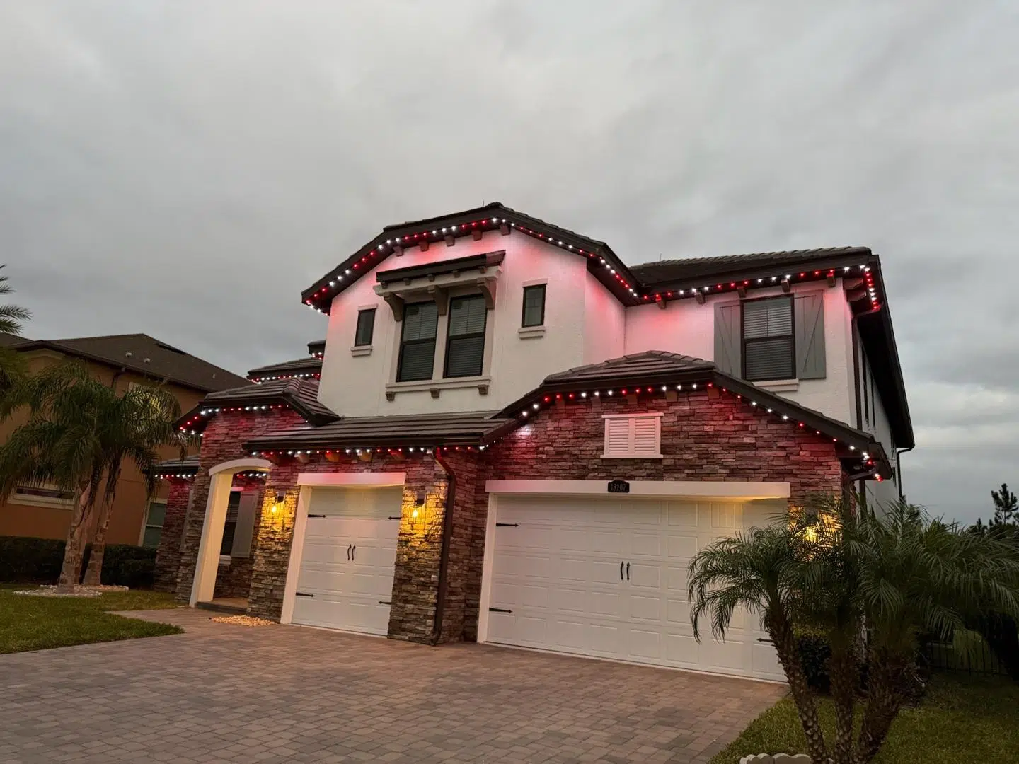 Soft white lights highlighting a two-story home’s entry and garage area in Cheval.