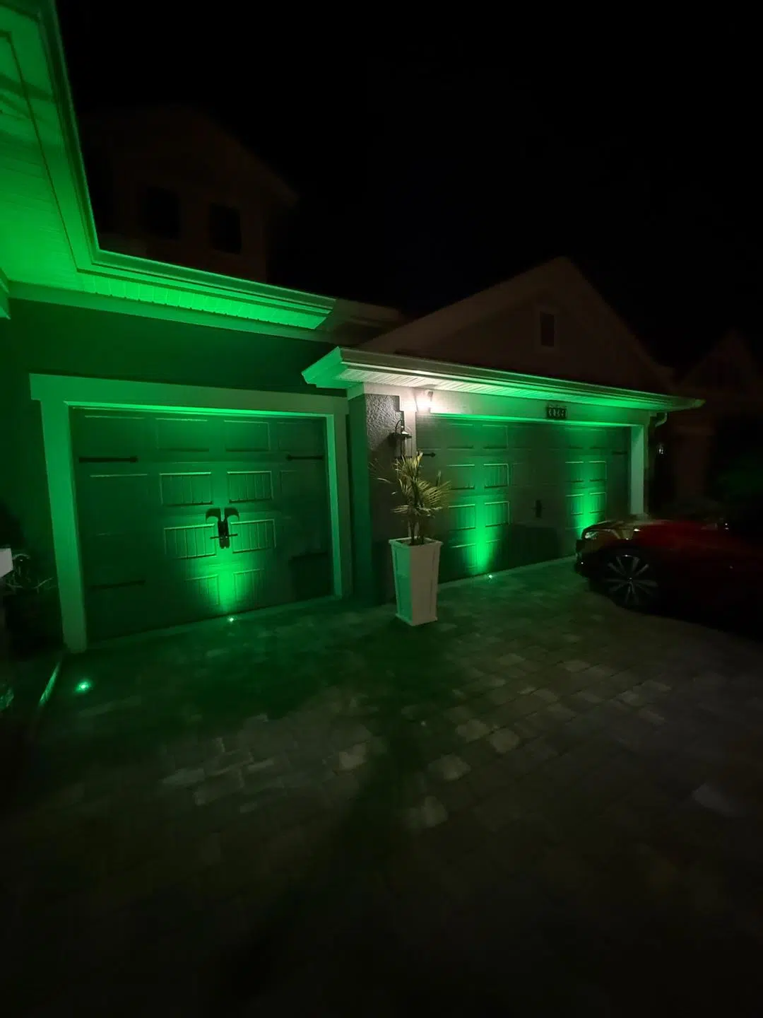 Bright green LED lighting on the garage and entry pillars of a Trinity home at night.