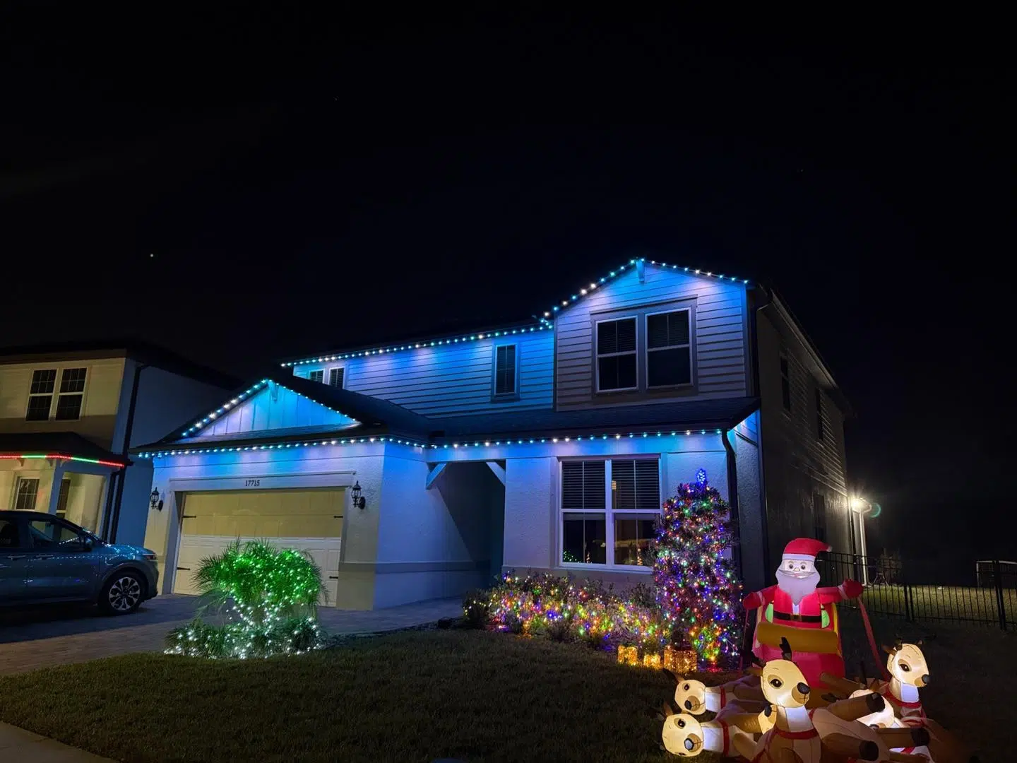 Bright blue holiday lighting with seasonal yard decor on a Palm Harbor home.