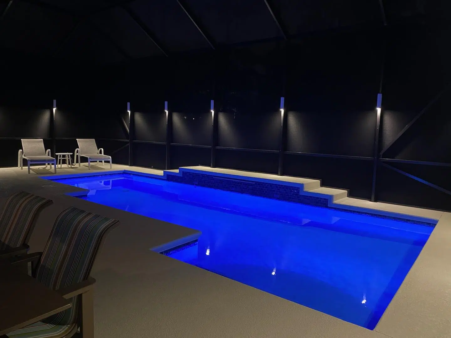 Blue LED lighting along the walls of a screened-in pool area in a Spring Hill backyard.