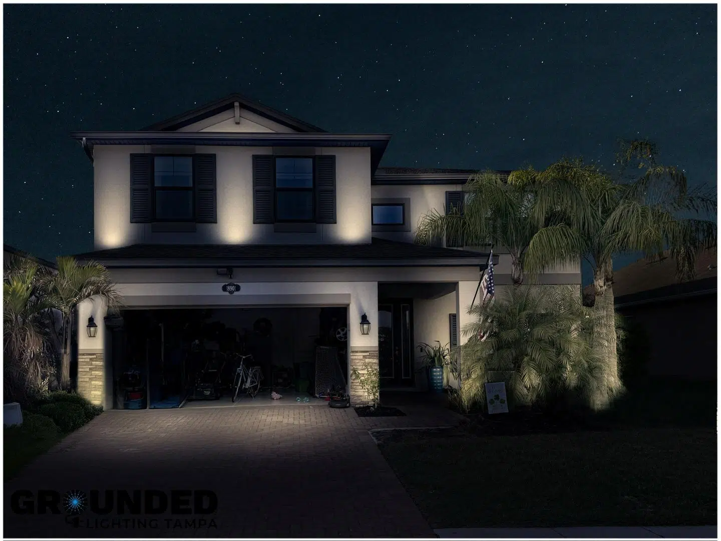 Subtle outdoor lighting on a two-story Trinity home at night, highlighting palm trees and garage.