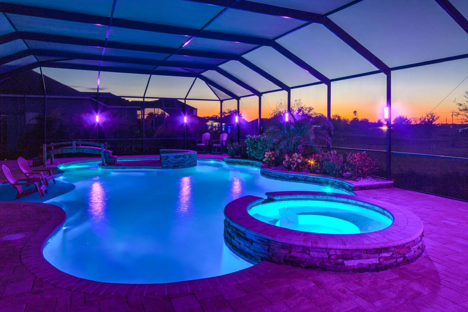 Colorful LED lighting in a pool and hot tub under a screened enclosure in Land O' Lakes.