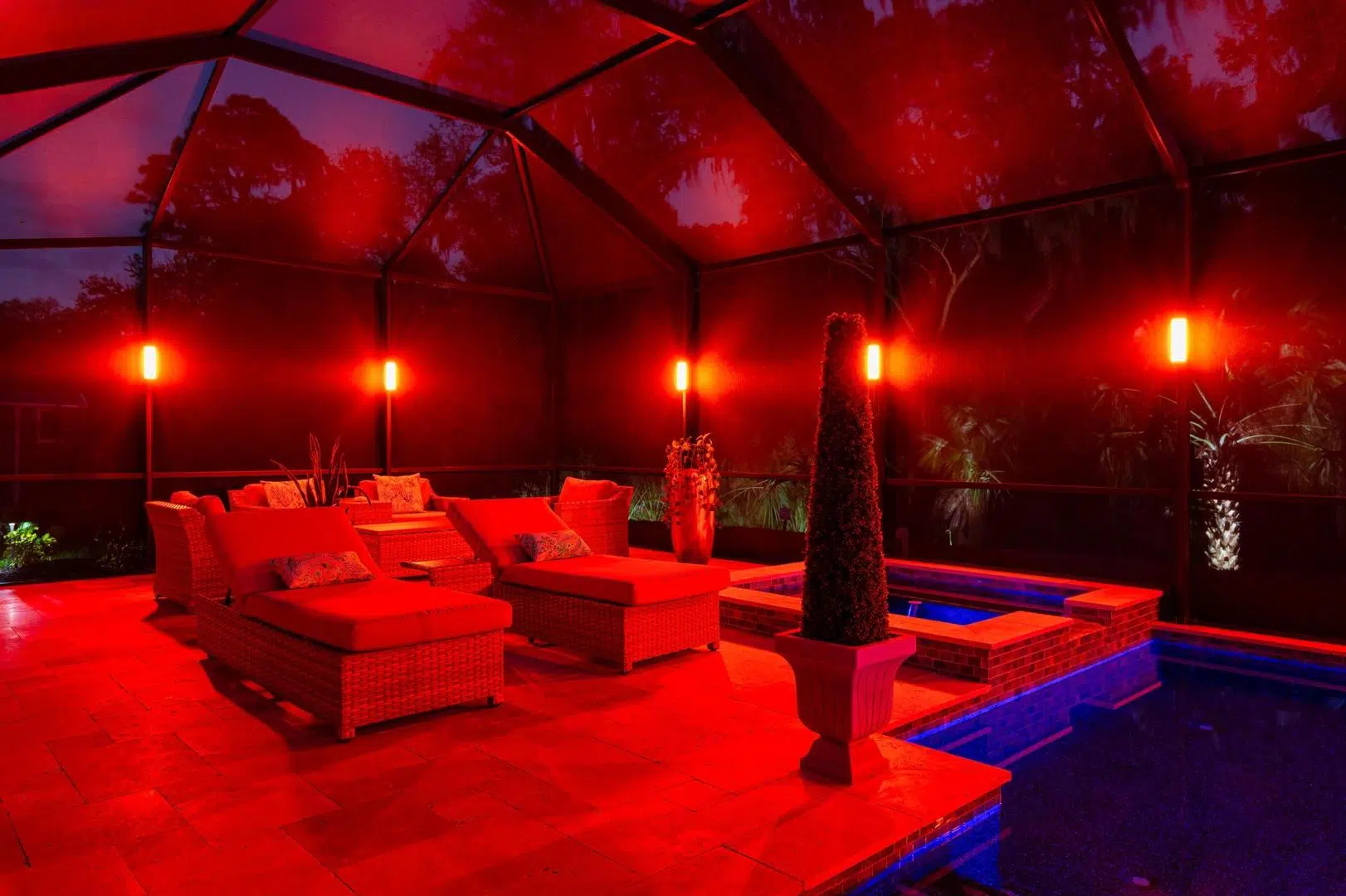 Red LED lighting over a covered pool and patio lounge area in a Palm Harbor backyard.