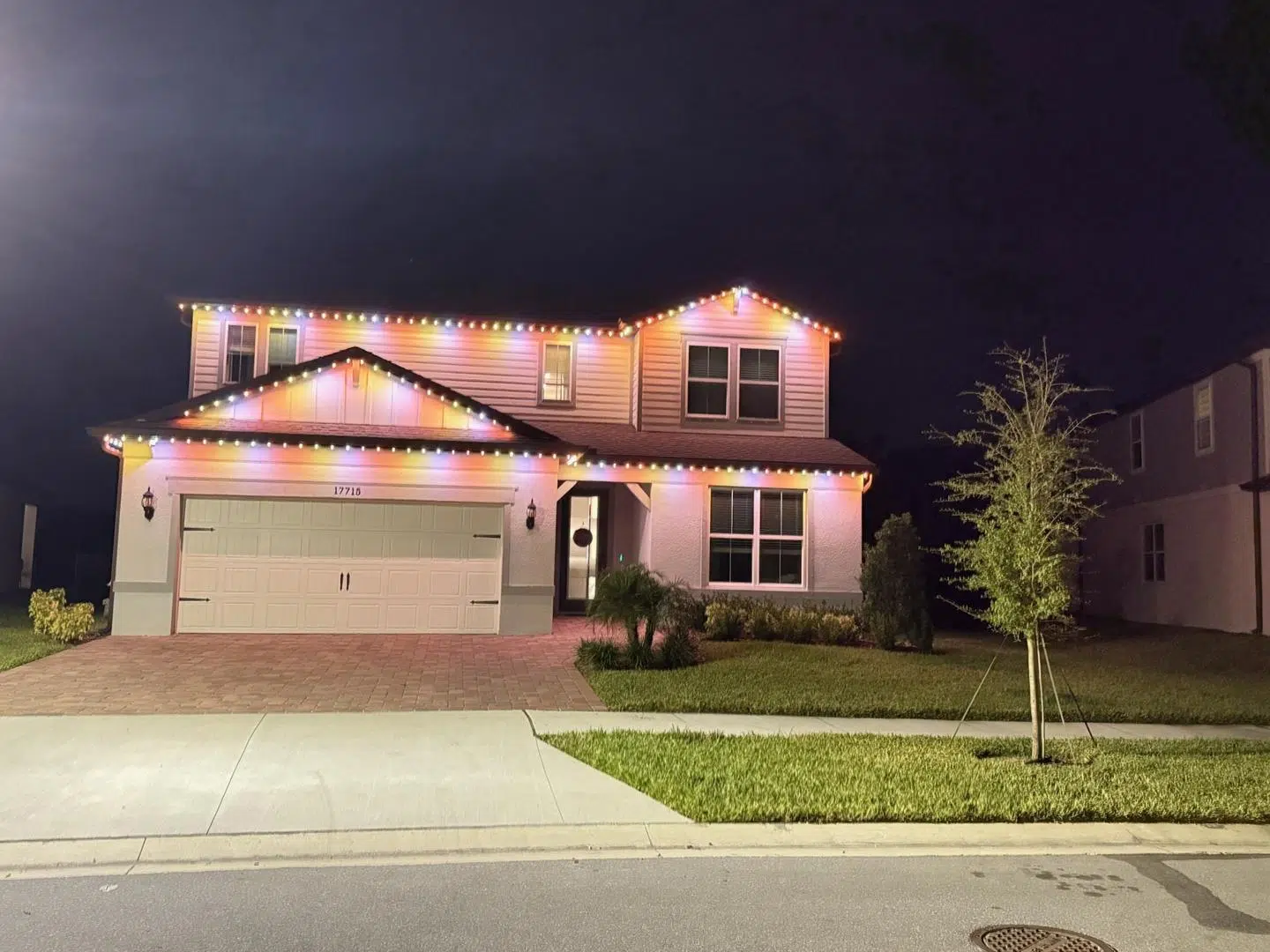 Colorful LED lighting outlining the roofline of a two-story Palm Harbor home at night.