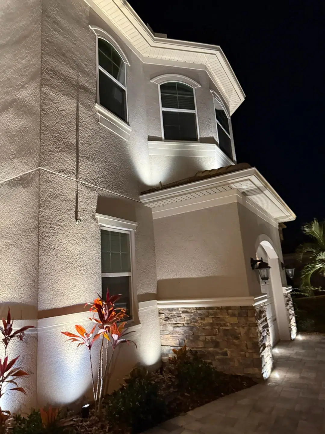 Bright white lighting on a two-story Land O’ Lakes home with detailed stonework.