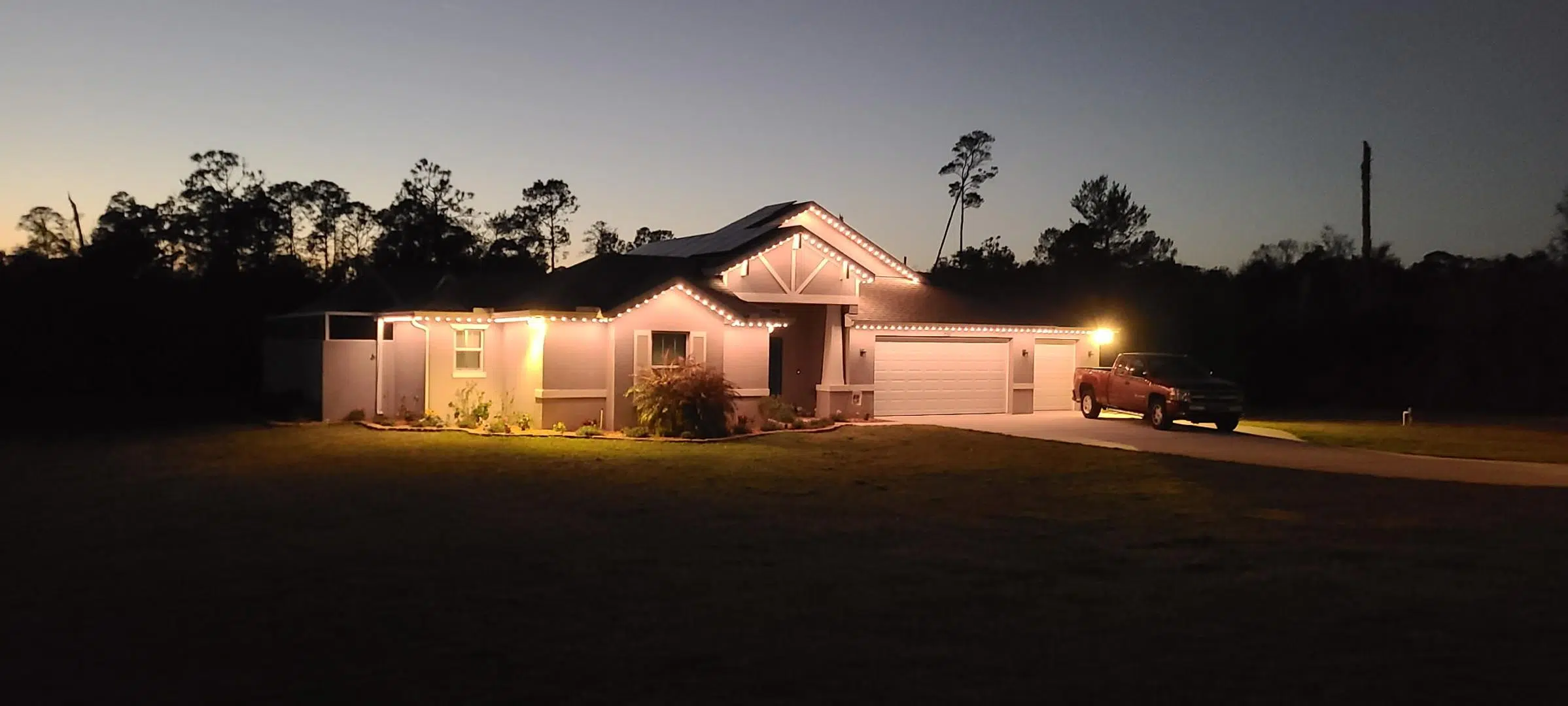 Front yard lighting with a warm amber tone on a Lutz home at dusk.